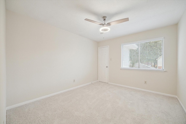 unfurnished room with baseboards, ceiling fan, and light colored carpet