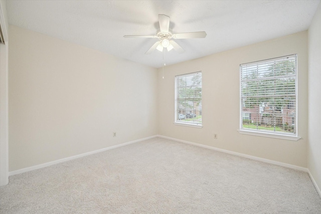 spare room featuring light carpet, ceiling fan, and baseboards