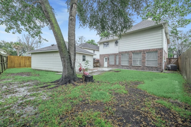 rear view of house with a yard, brick siding, and a fenced backyard