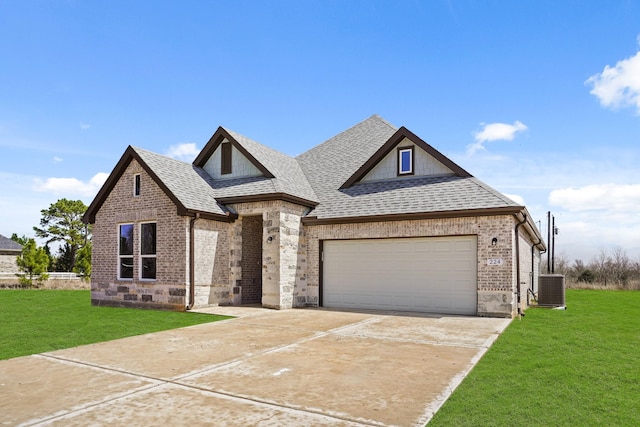 view of front facade with central AC, a shingled roof, brick siding, driveway, and a front yard