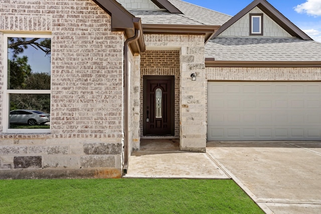 view of exterior entry featuring a garage, a shingled roof, brick siding, stone siding, and concrete driveway