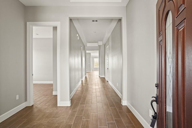 hallway with wood tiled floor, visible vents, and baseboards