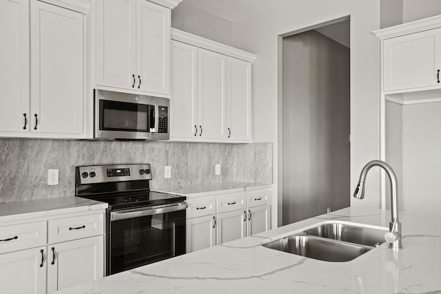 kitchen with appliances with stainless steel finishes, white cabinets, a sink, and decorative backsplash