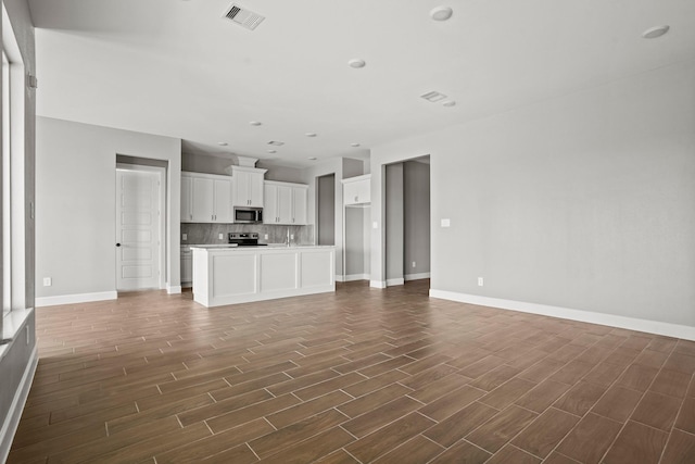 unfurnished living room with recessed lighting, visible vents, dark wood finished floors, and baseboards