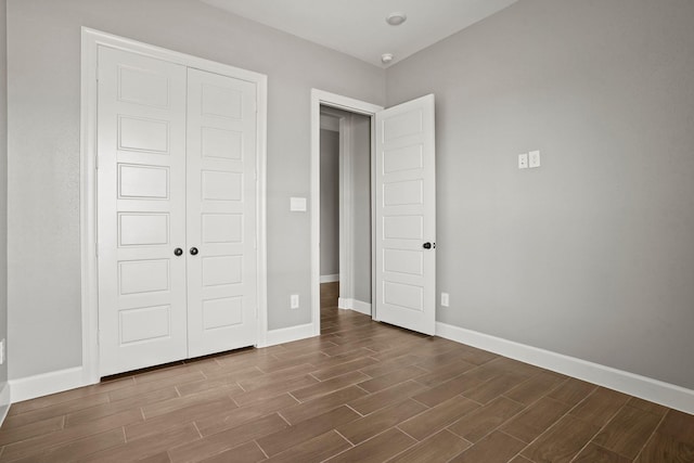 unfurnished bedroom with baseboards, a closet, and wood tiled floor