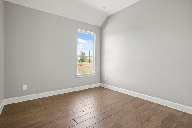 empty room with lofted ceiling, wood tiled floor, and baseboards