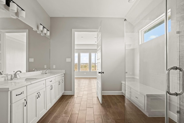 full bathroom with baseboards, wood finish floors, a sink, and a shower stall