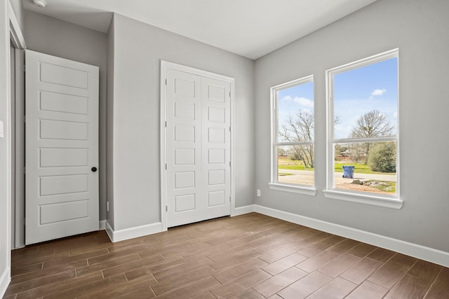 unfurnished bedroom with dark wood-style floors, a closet, and baseboards