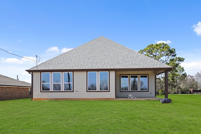 rear view of house featuring a shingled roof and a yard