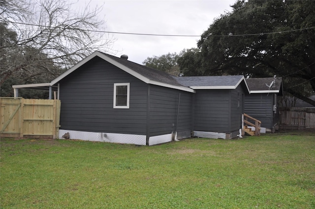 back of property featuring fence, a lawn, and roof with shingles