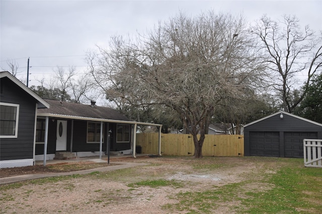 view of yard featuring a detached garage, covered porch, a gate, fence, and an outdoor structure