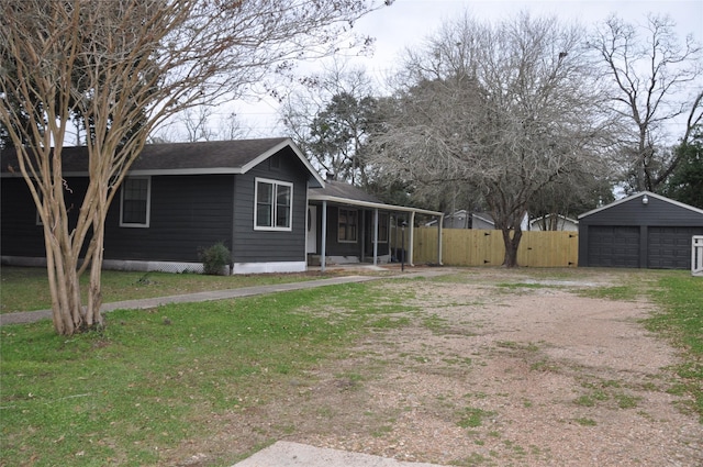 view of front of house featuring a porch, an outdoor structure, fence, a detached garage, and a front lawn