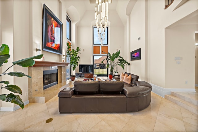 living area featuring a chandelier, a high ceiling, baseboards, and a premium fireplace