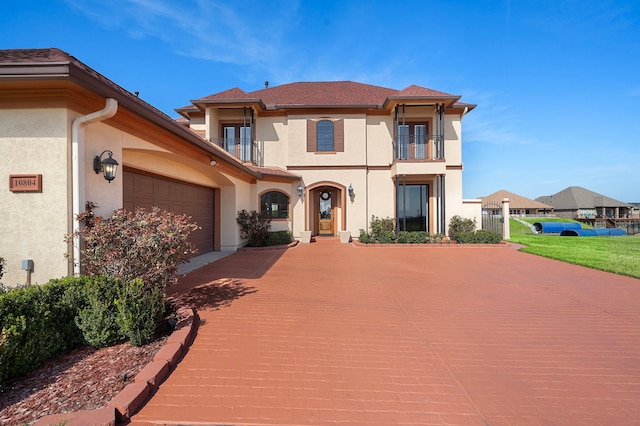 10804 Bourbon St, Willis, TX 77318 - mediterranean / spanish-style house featuring a balcony, stucco siding, and an attached garage