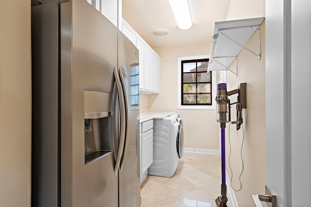 interior space with washer and clothes dryer, light countertops, light tile patterned flooring, white cabinetry, and stainless steel fridge