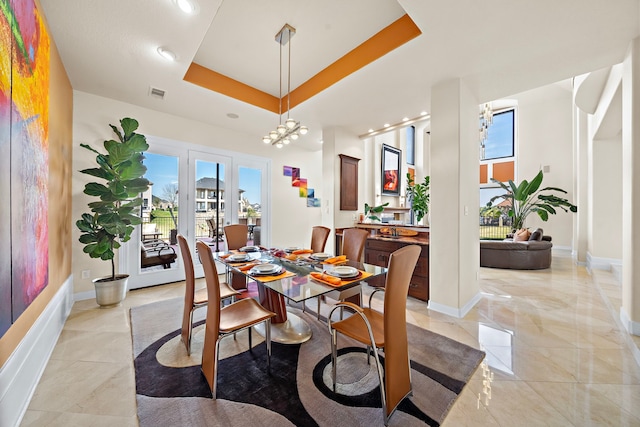 dining space featuring baseboards, visible vents, and a raised ceiling