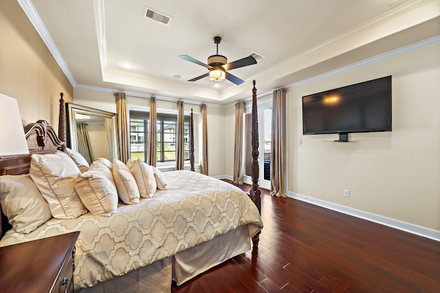 bedroom featuring dark wood-style flooring, a raised ceiling, visible vents, ornamental molding, and baseboards