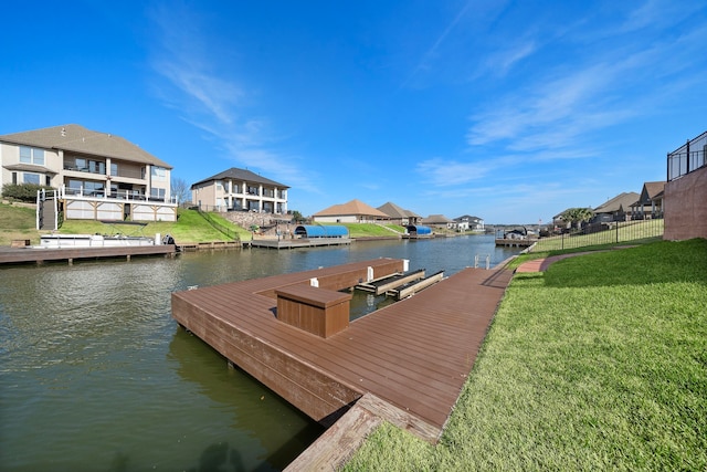 view of dock with a lawn and a water view