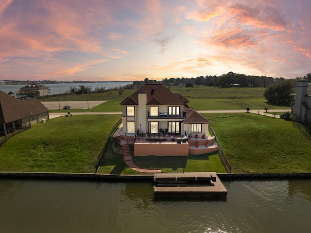 view of play area with a water view, a lawn, a boat dock, and a patio