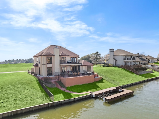 rear view of house featuring a fenced backyard, a balcony, a water view, a yard, and a patio area