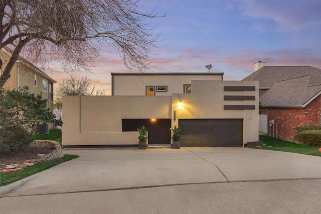 view of front facade featuring a garage, concrete driveway, and stucco siding