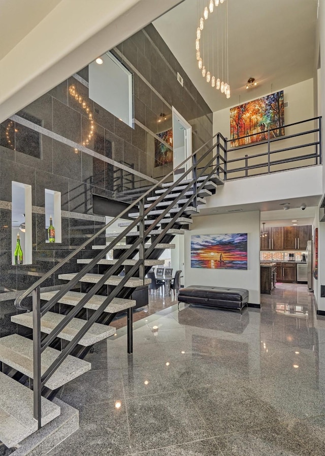 stairs featuring granite finish floor and a high ceiling