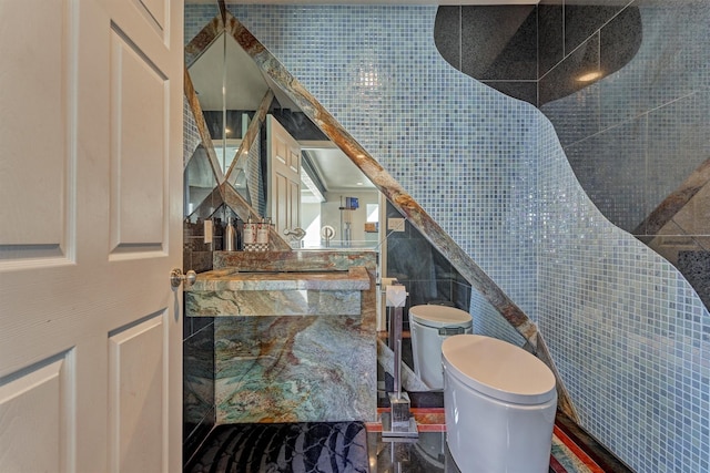 bathroom featuring toilet and tile walls