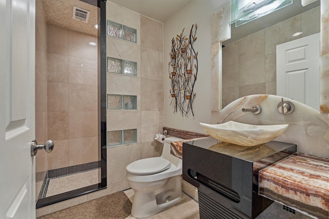 full bath with visible vents, toilet, tile patterned floors, vanity, and tile walls