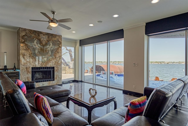 living room featuring recessed lighting, a large fireplace, a water view, and crown molding