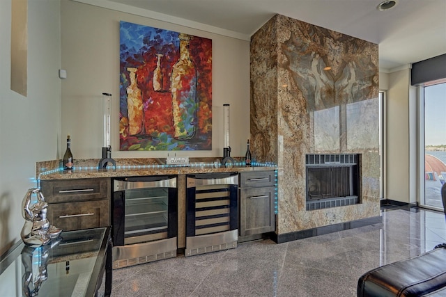 bar featuring wine cooler, indoor wet bar, granite finish floor, and a tiled fireplace