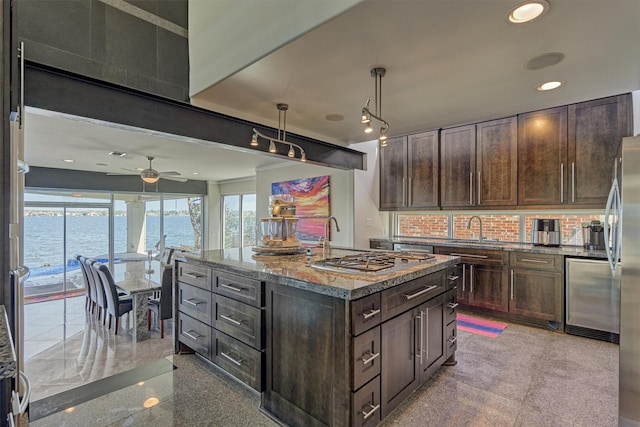 kitchen featuring a water view, granite finish floor, dark brown cabinets, a center island with sink, and pendant lighting