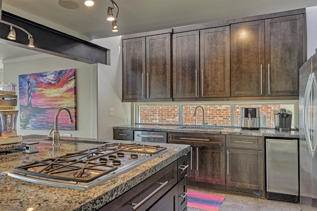 kitchen featuring a sink, backsplash, dark brown cabinets, and light stone countertops