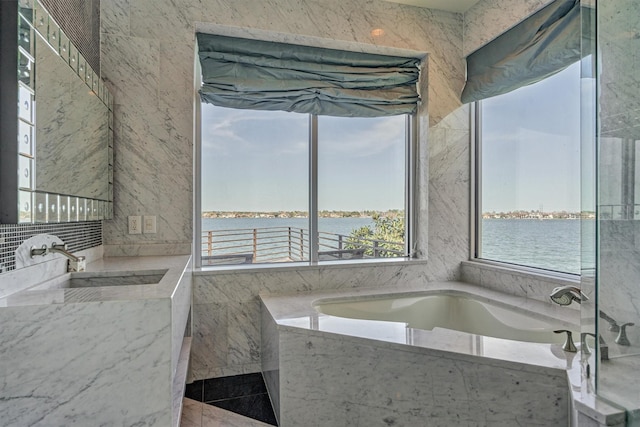 bathroom featuring a water view, a sink, and a bath