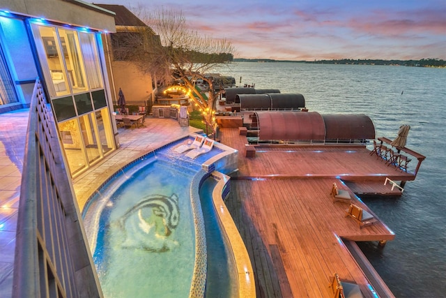 pool at dusk featuring a water view, a patio area, and a jacuzzi