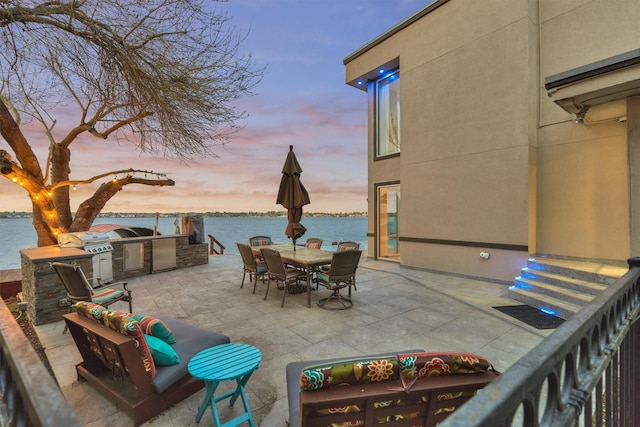 view of patio / terrace featuring exterior kitchen, outdoor dining area, and a water view