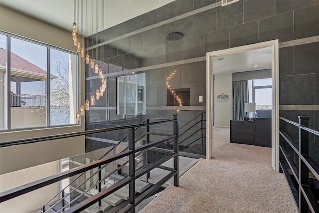 corridor with a healthy amount of sunlight, visible vents, carpet flooring, and an upstairs landing