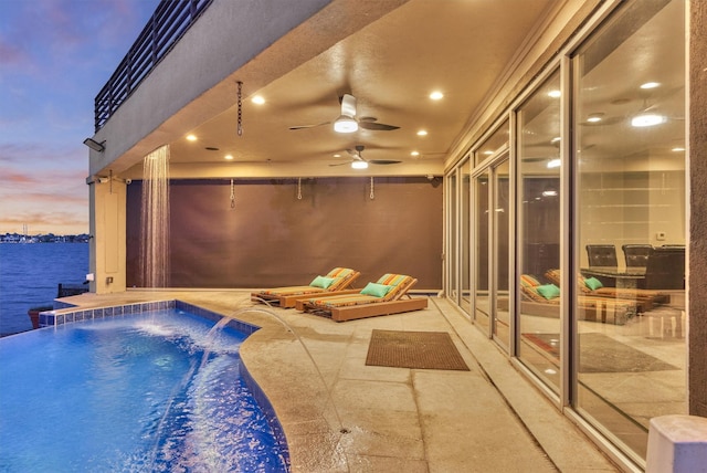 outdoor pool with a water view, ceiling fan, and a patio