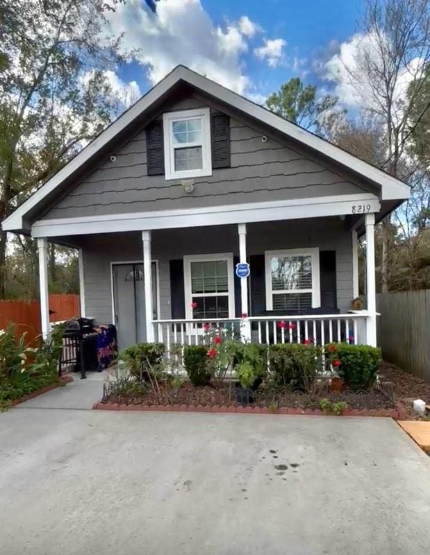 bungalow-style house with covered porch and fence