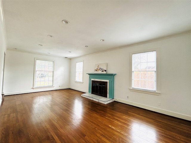 unfurnished living room featuring crown molding, dark wood-style flooring, a glass covered fireplace, and baseboards