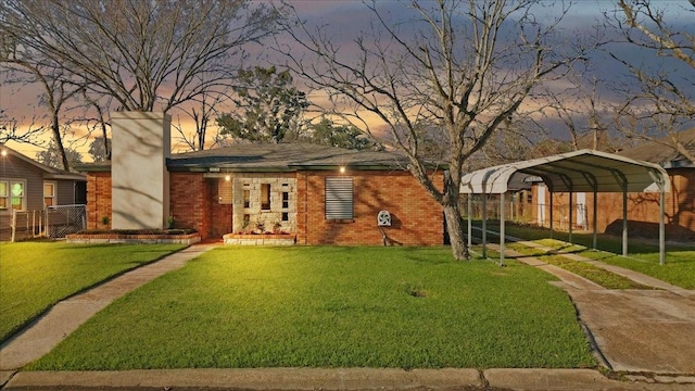 view of front of property featuring a carport, fence, a lawn, and brick siding