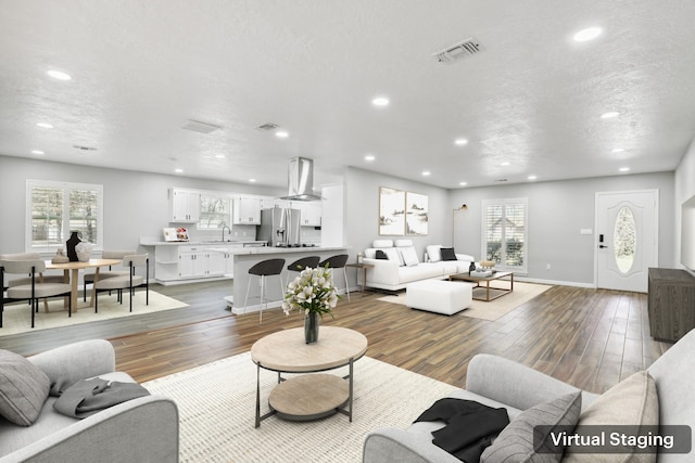 living area featuring visible vents, plenty of natural light, a textured ceiling, and wood finished floors