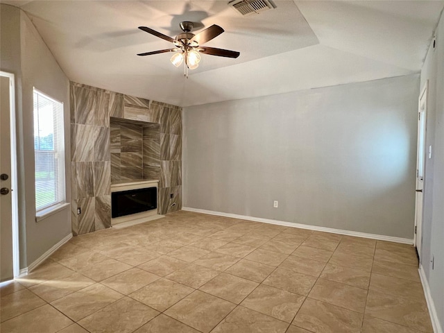 unfurnished living room with baseboards, a tiled fireplace, visible vents, and a ceiling fan