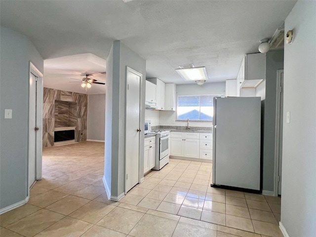 kitchen with white appliances, white cabinets, a ceiling fan, under cabinet range hood, and a sink