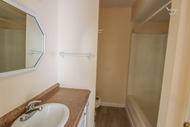 bathroom featuring wood finished floors, vanity, toilet, and baseboards