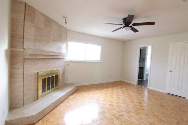 unfurnished living room with a ceiling fan, a large fireplace, and baseboards