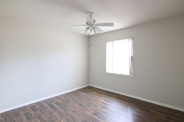 spare room featuring ceiling fan, baseboards, and dark wood finished floors