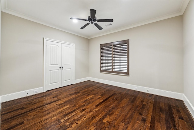 unfurnished bedroom with dark wood-style flooring, a closet, visible vents, ornamental molding, and baseboards