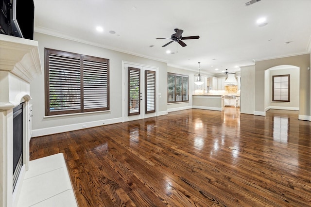 unfurnished living room with a fireplace, ornamental molding, a ceiling fan, and wood finished floors