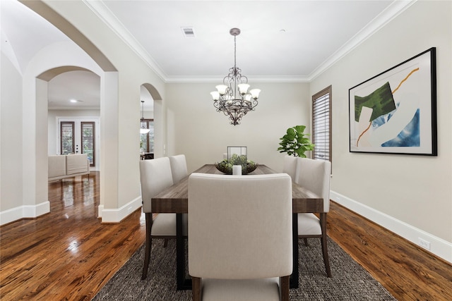 dining area featuring baseboards, arched walkways, dark wood-style floors, ornamental molding, and a notable chandelier