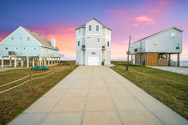 view of front facade featuring a yard, driveway, a garage, and central AC unit